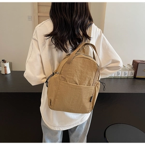 Vue arrière d'un mini sac à dos en nylon kaki porté par un mannequin en intérieur