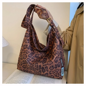 Detail view of the leopard print tote bag with metallic adjustable strap and brand tag