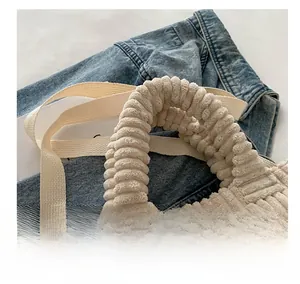 Detail of cream corduroy bucket bag with pleated handle and adjustable canvas strap