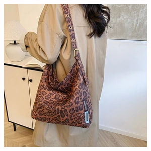 Detail of vintage leopard print tote bag with adjustable metal eyelet strap on model