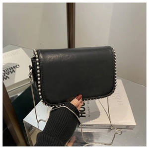 Detail of black faux leather crossbody bag with silver studs and chain shoulder strap