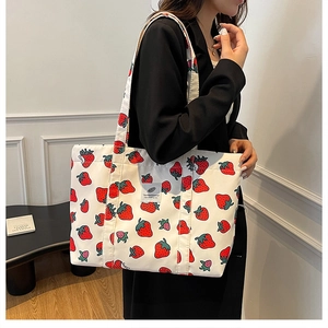 Detail of strawberry print tote bag showing the textured canvas and fabric logo patch