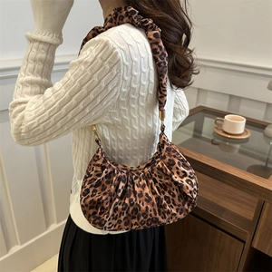 Detail view of the pleated leopard print shoulder bag with gold metal buckle and strap