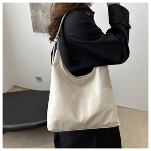 Detail view of cream leather tote bag featuring center stitching and adjustable shoulder strap
