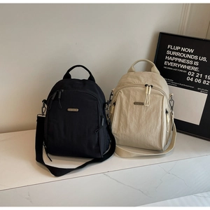 Detail view of stylish black and beige nylon backpacks on a marble surface background