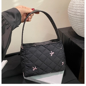 Gros plan d'un sac cabas matelassé noir avec broderie nœud rose et texture en tissu