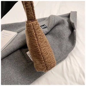 Détail rapproché de la texture du sac seau marron en peluche sur fond de manteau en laine grise