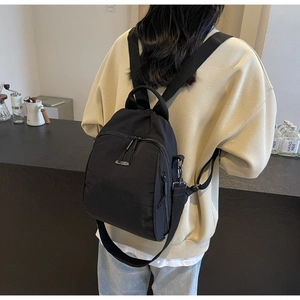 Close-up of black nylon backpack showing waterproof texture and metal logo plaque