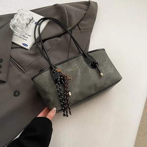 Textured large capacity dark gray tote bag with woven charm on a stylish blazer background