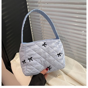 Détail du sac seau matelassé bleu clair avec broderies de nœuds noirs élégants