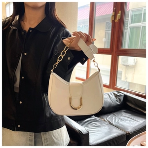 Detail of white crescent shoulder bag with golden U-shaped buckle and metal chain strap