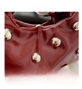 Détail du sac en cuir verni bordeaux avec de grands clous sphériques en métal argenté