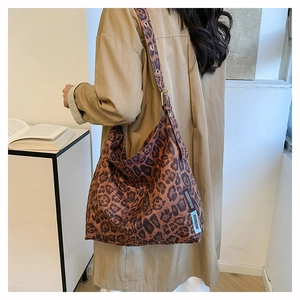 Detail of leopard print canvas tote bag featuring adjustable strap and side brand label