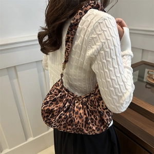 Detail of leopard print ruched underarm bag featuring golden metal buckles and zipper