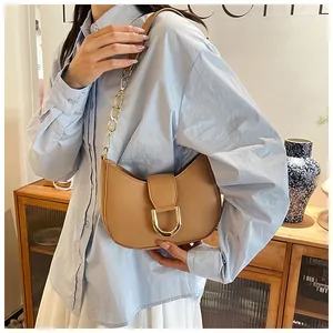 Detail of light khaki leather half-moon bag with large gold buckle and chain strap