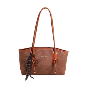 Brown textured tote bag with glossy handles and tennis racket charm accessory