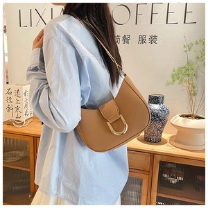 Detail of camel crescent shoulder bag with golden metal buckle in a lifestyle setting