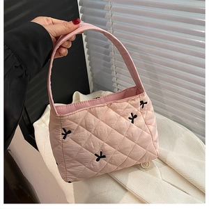 Détail du sac cabas rose matelassé avec broderies de nœuds noirs et tissu doux au toucher