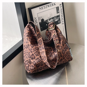 Detail view of leopard print tote bag with adjustable strap and metal buckle on table