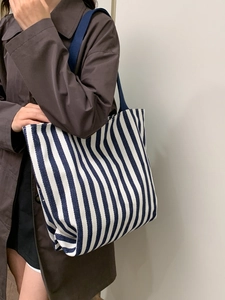 Detailed close-up of a blue and white striped canvas tote bag with woven shoulder straps