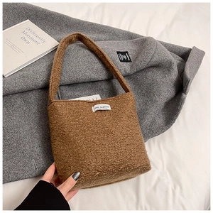 Gros plan du sac seau en peluche marron avec étiquette LOVE FASHION et texture douce