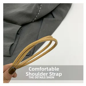 Detailed view of khaki tubular shoulder strap with fine stitching on grey fabric background