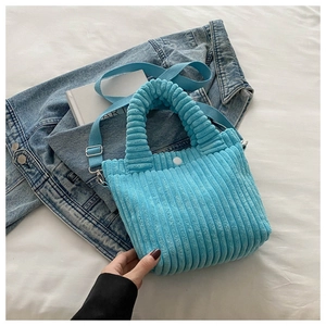 Detailed close-up of blue corduroy bucket bag texture with top handle and strap