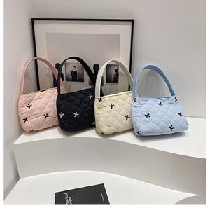 Détail rapproché de sacs cabas matelassés en rose, noir, blanc cassé et bleu clair