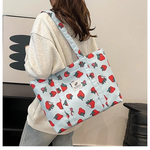 Detail view of large light blue canvas tote bag with red strawberry print on shoulder