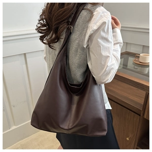 Deep brown large hobo shoulder bag with vertical stitching in a cozy lifestyle setting