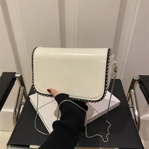White faux leather chain crossbody bag with decorative silver beaded edges and flap closure