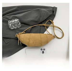 Detail view of khaki suede croissant bag with adjustable knotted rope strap and pleated seams