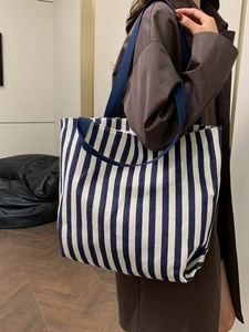 Detail showing the large capacity blue and white striped canvas tote bag on model