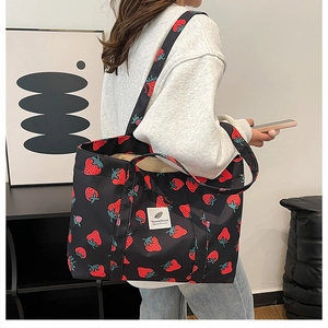 Close-up of strawberry print tote bag showing white label detail on black canvas