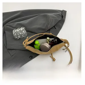 Detail view of khaki crescent shoulder bag interior holding phone and cosmetics