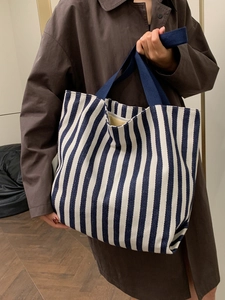 Detail showing blue and white striped canvas tote bag with sturdy woven navy straps