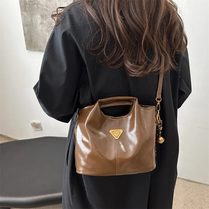 Vintage brown leather bucket bag with metallic triangle logo and decorative charm