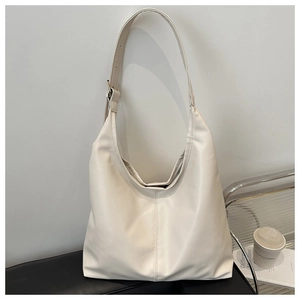 Detail of minimalist cream-white tote bag with adjustable strap on a dark display stand