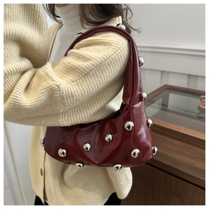 Détail du sac à main en cuir verni bordeaux avec de grands clous métalliques ronds argentés