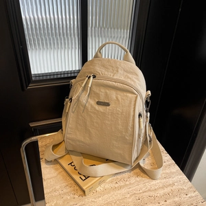 Minimalist beige nylon backpack with front pocket and adjustable straps on marble surface