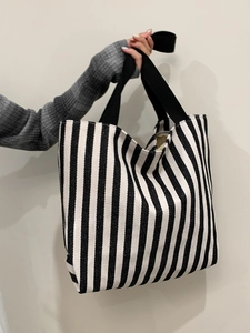 Detail of a large striped canvas tote bag with black woven handles and durable fabric texture