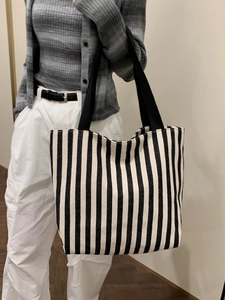 Detail of black and white striped canvas tote bag with wide black woven handles for daily use