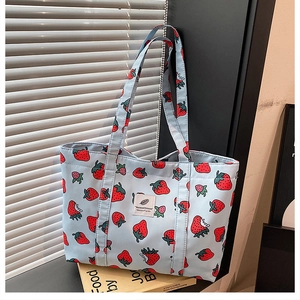 Close-up of the detailed strawberry print on the light blue canvas tote bag