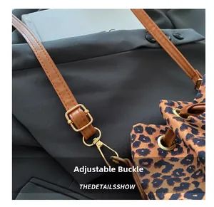 Close-up of leopard print bucket bag with adjustable brown leather strap and metal buckle