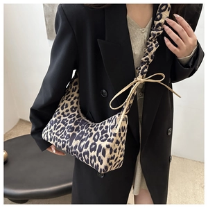 Detailed close-up of leopard print crescent bag with ruffled strap and bow detail