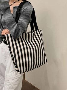 Close-up of black and white vertical striped canvas tote bag with wide black shoulder straps