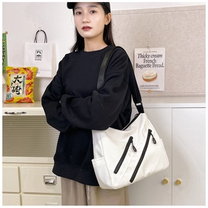 Détail du sac bandoulière blanc minimaliste en nylon avec fermetures éclair noires en diagonale