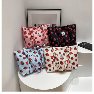 Detailed display of strawberry print canvas tote bags in four vibrant color options