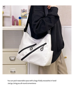 Détail du sac hobo en nylon blanc avec fermetures éclair diagonales noires parallèles