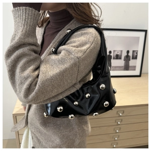 Sac sous le bras chic en cuir verni noir avec gros clous argentés sur un mannequin